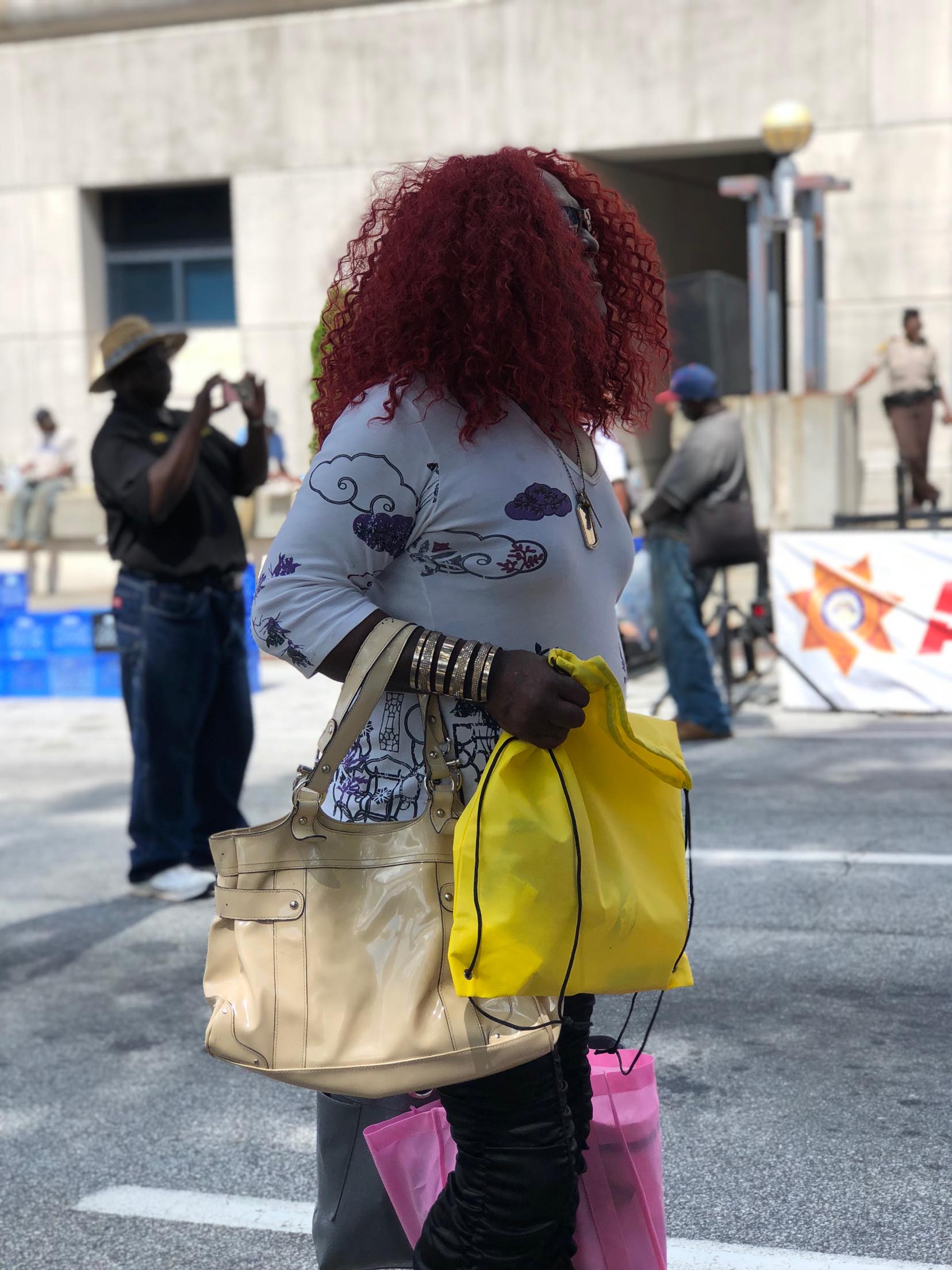 A woman with red curly hair holding yellow and pink Jo-Anne's House bags at the outreach