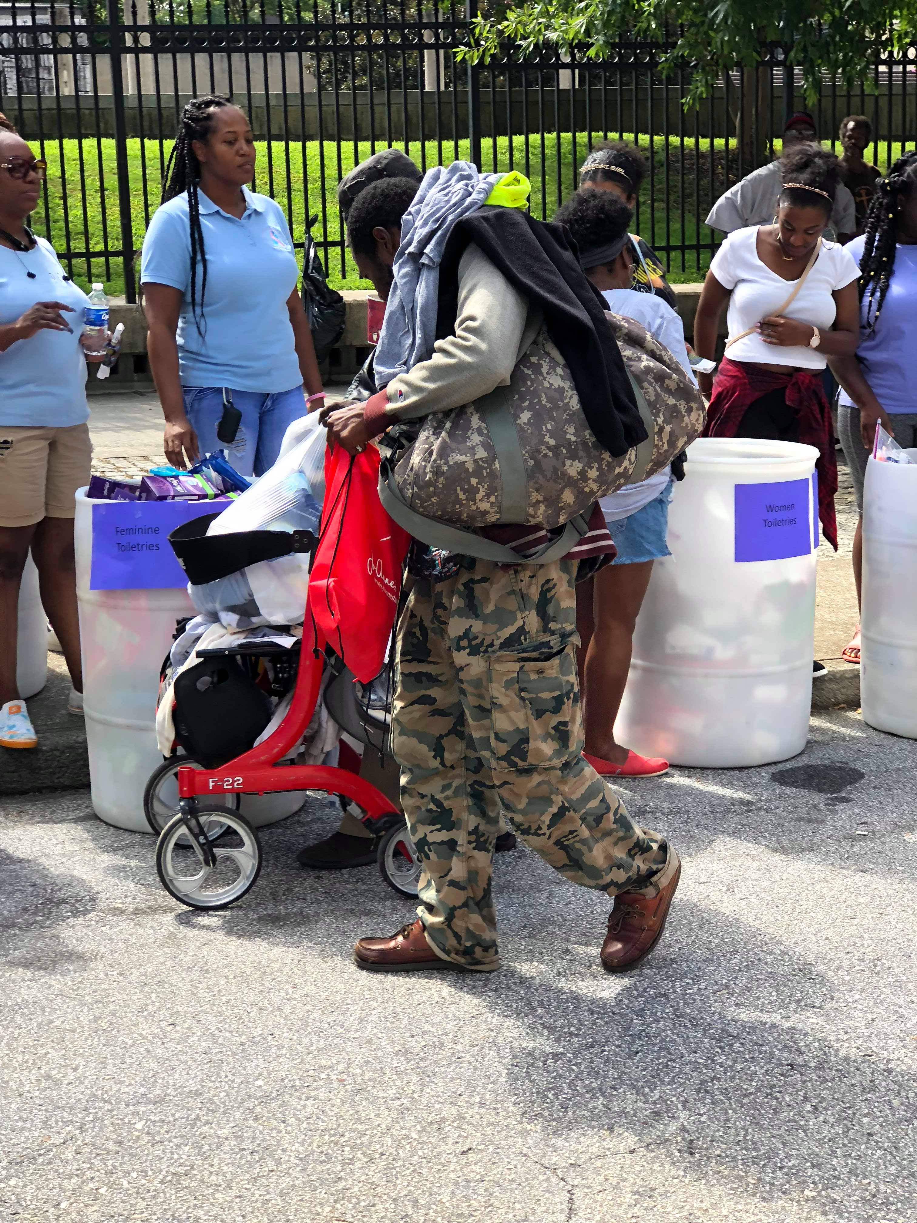A man carrying his belongings past barrels of donated toiletries at the outreach