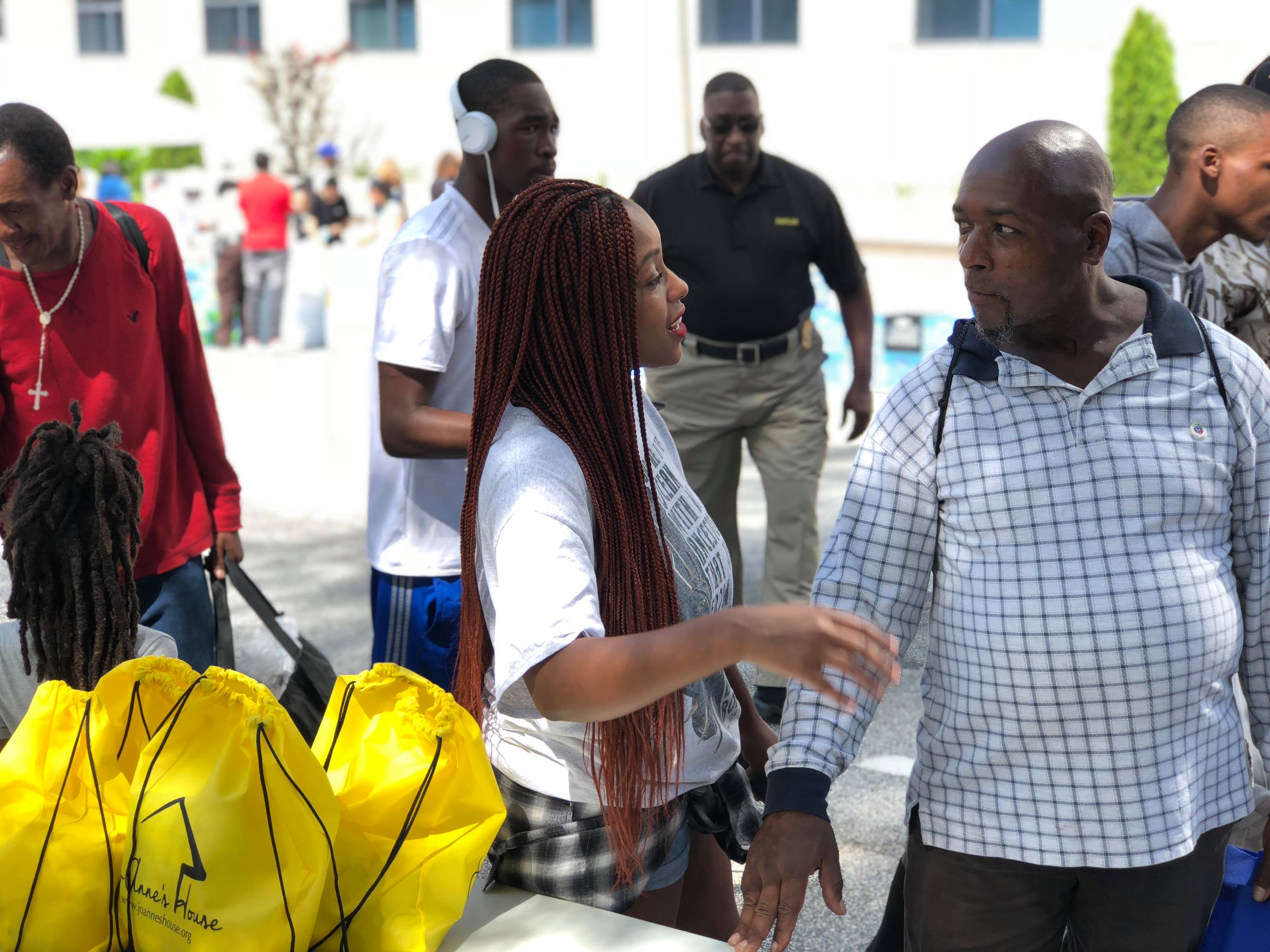 A Jo-Anne's House volunteer talking with a man beside a table of yellow care bags