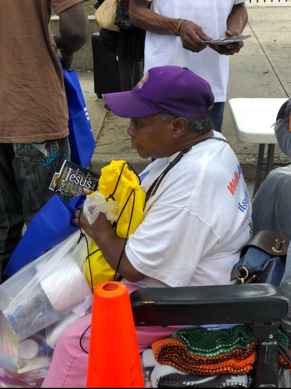 A man in a wheelchair holding a yellow care bag and a pamphlet at the outreach
