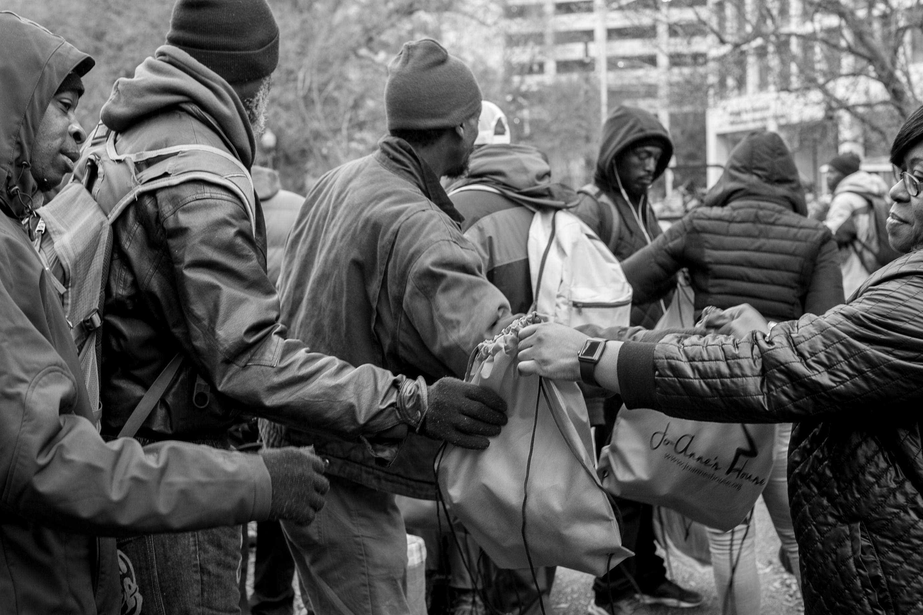 Volunteers passing Jo-Anne's House care bags down a line of recipients