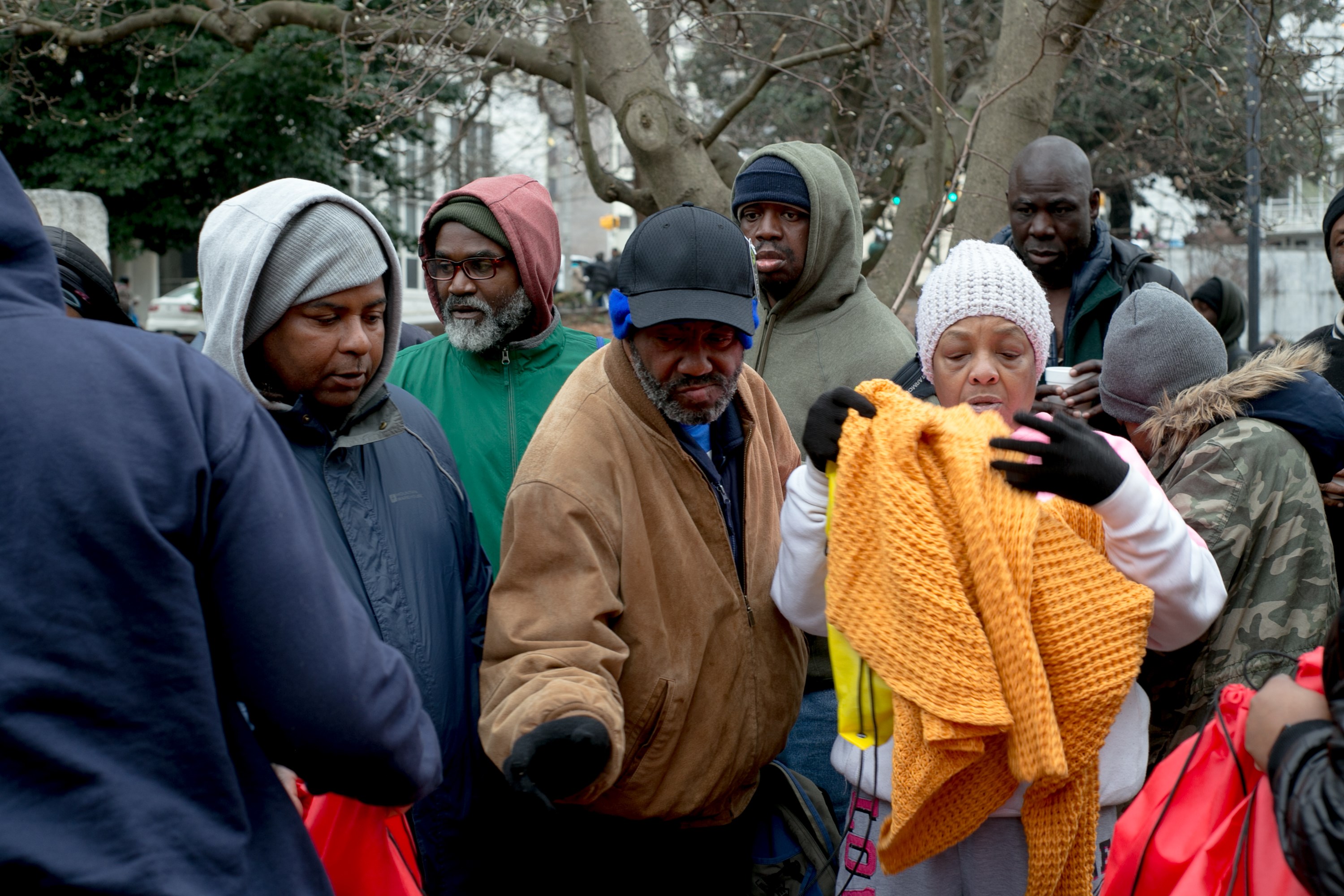 A woman receiving an orange knit blanket among the crowd at the outreach