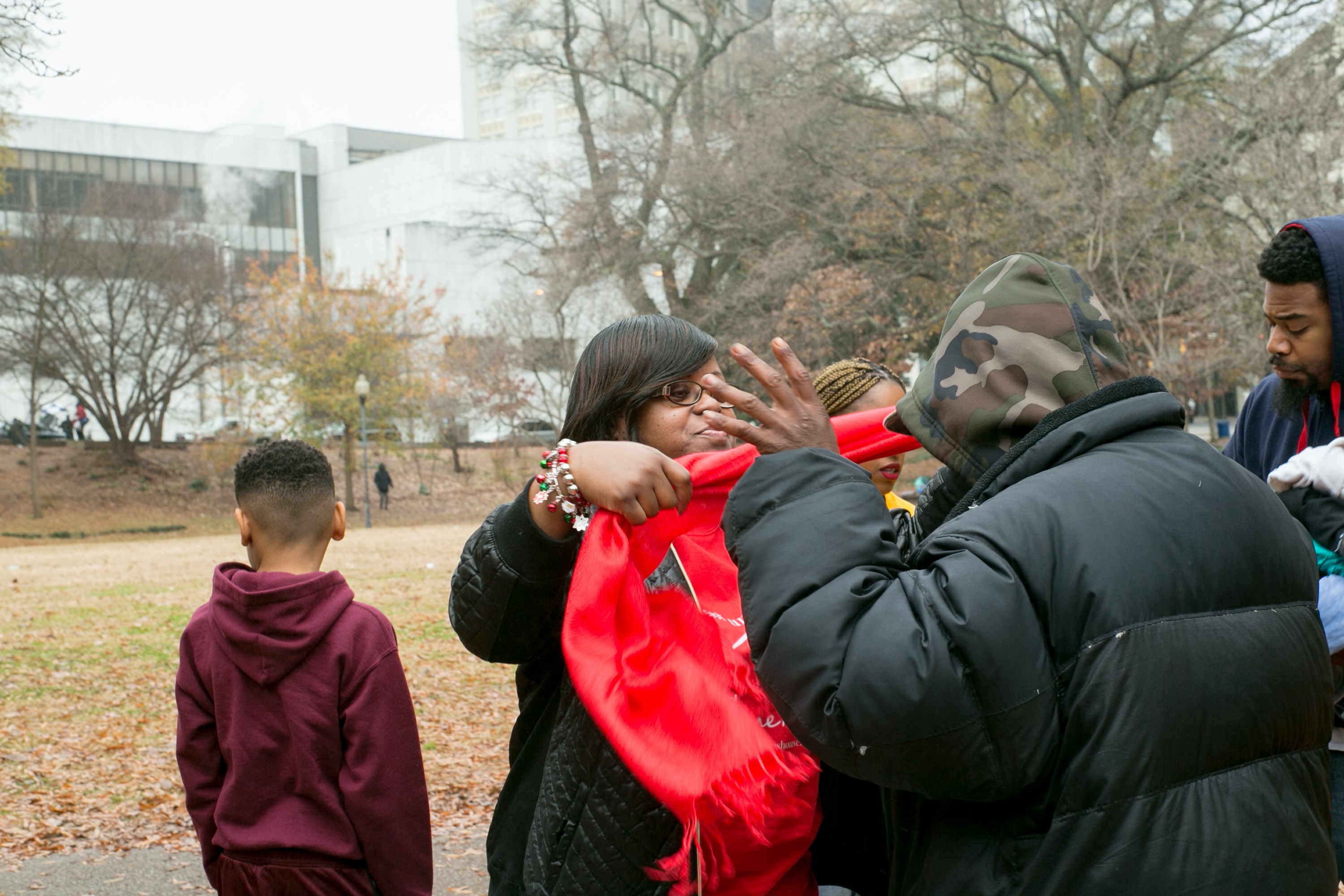 A volunteer wrapping a warm red scarf around a community member