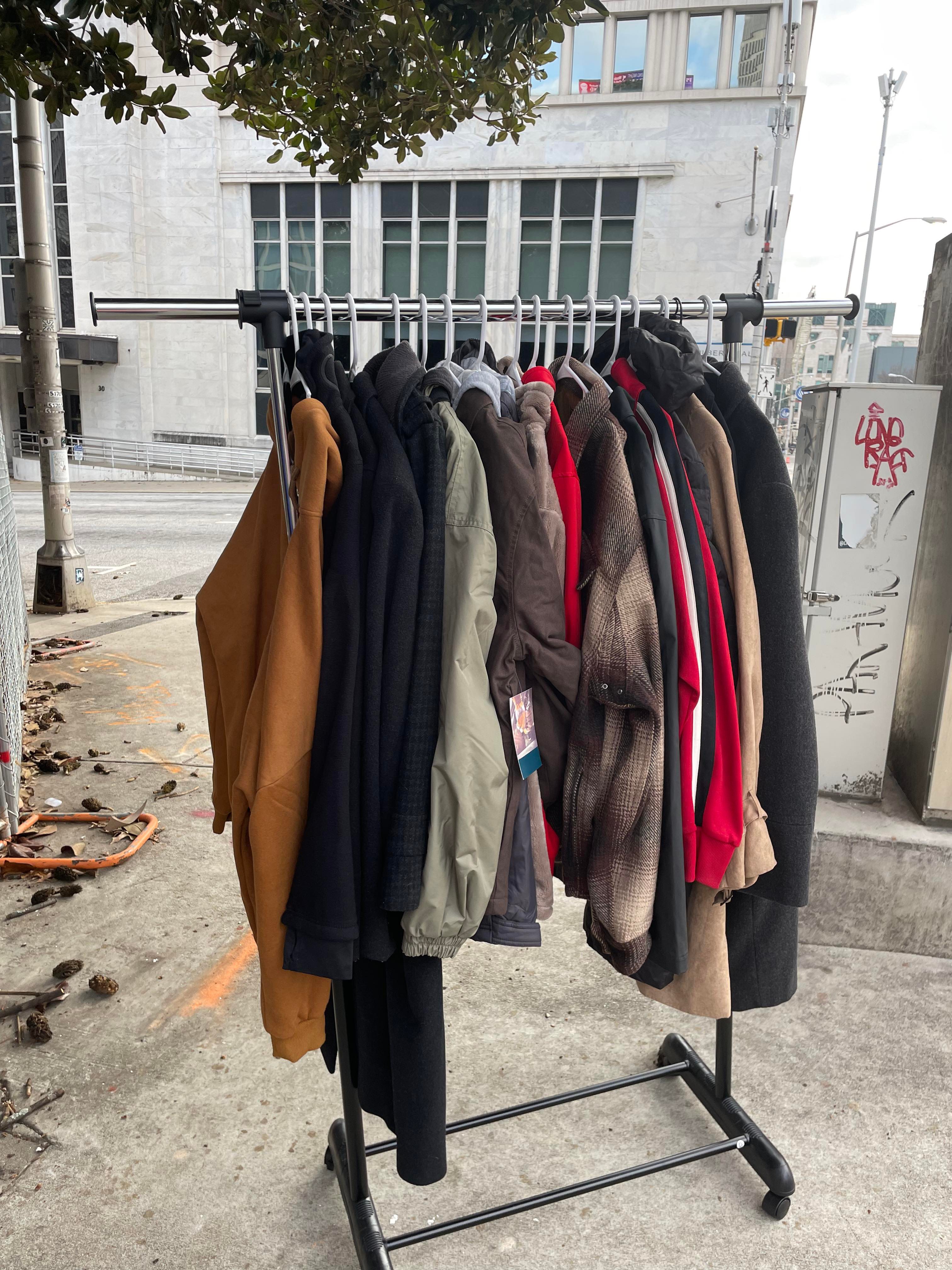 A rack of donated coats and jackets set up on the sidewalk for the outreach