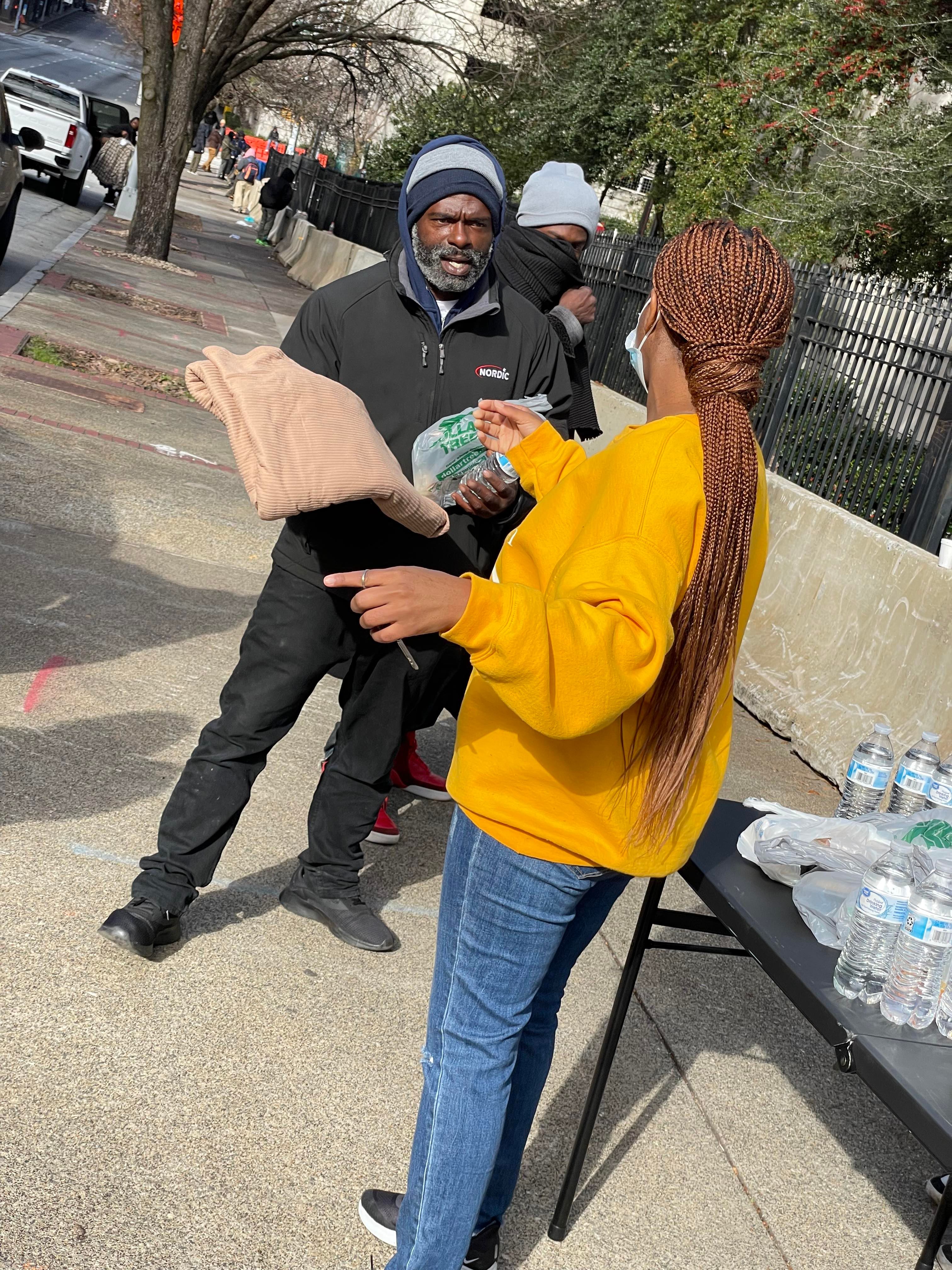 A volunteer handing donated items to a community member on the street