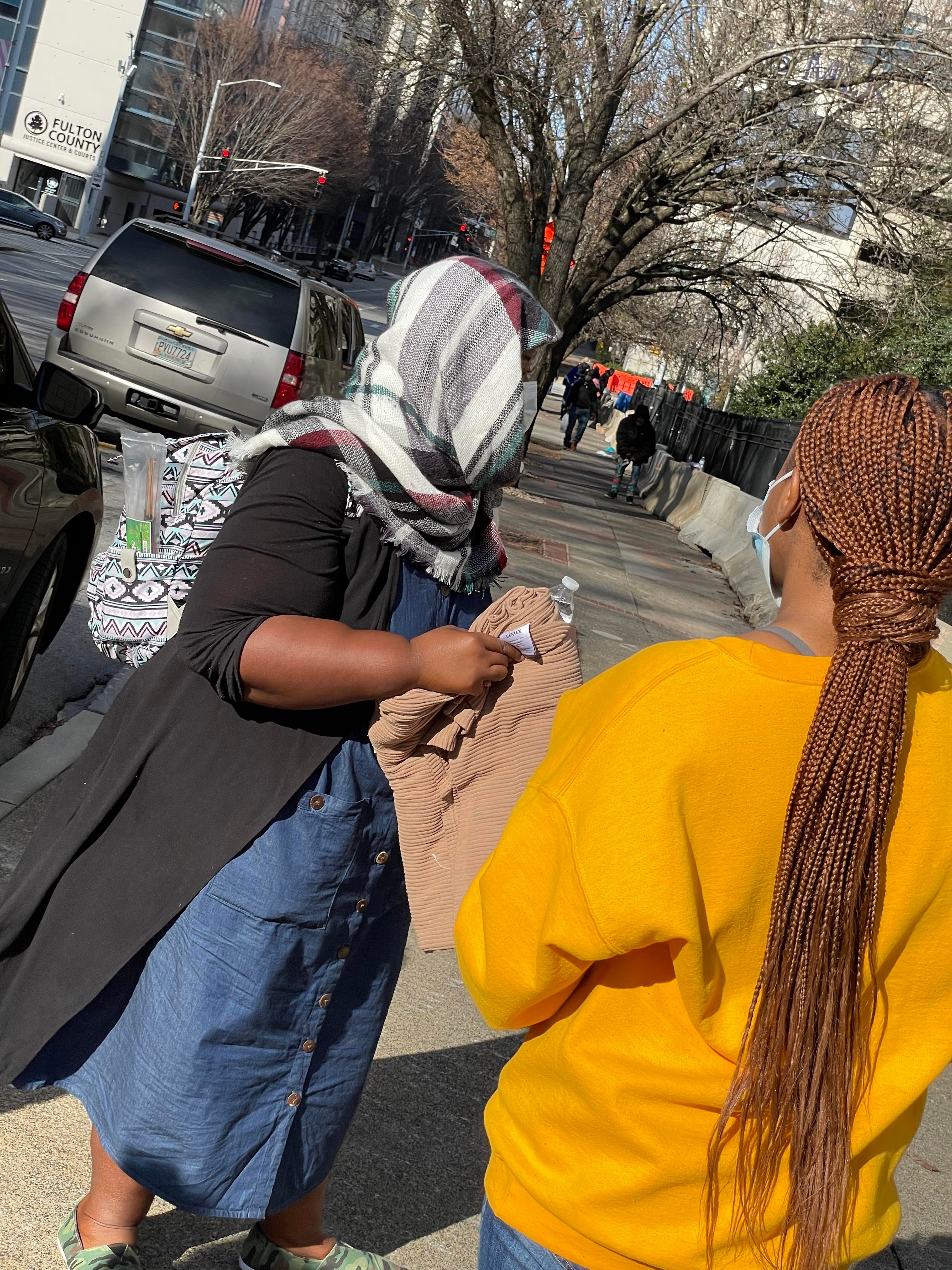 A volunteer giving folded blankets to a woman wearing a headscarf