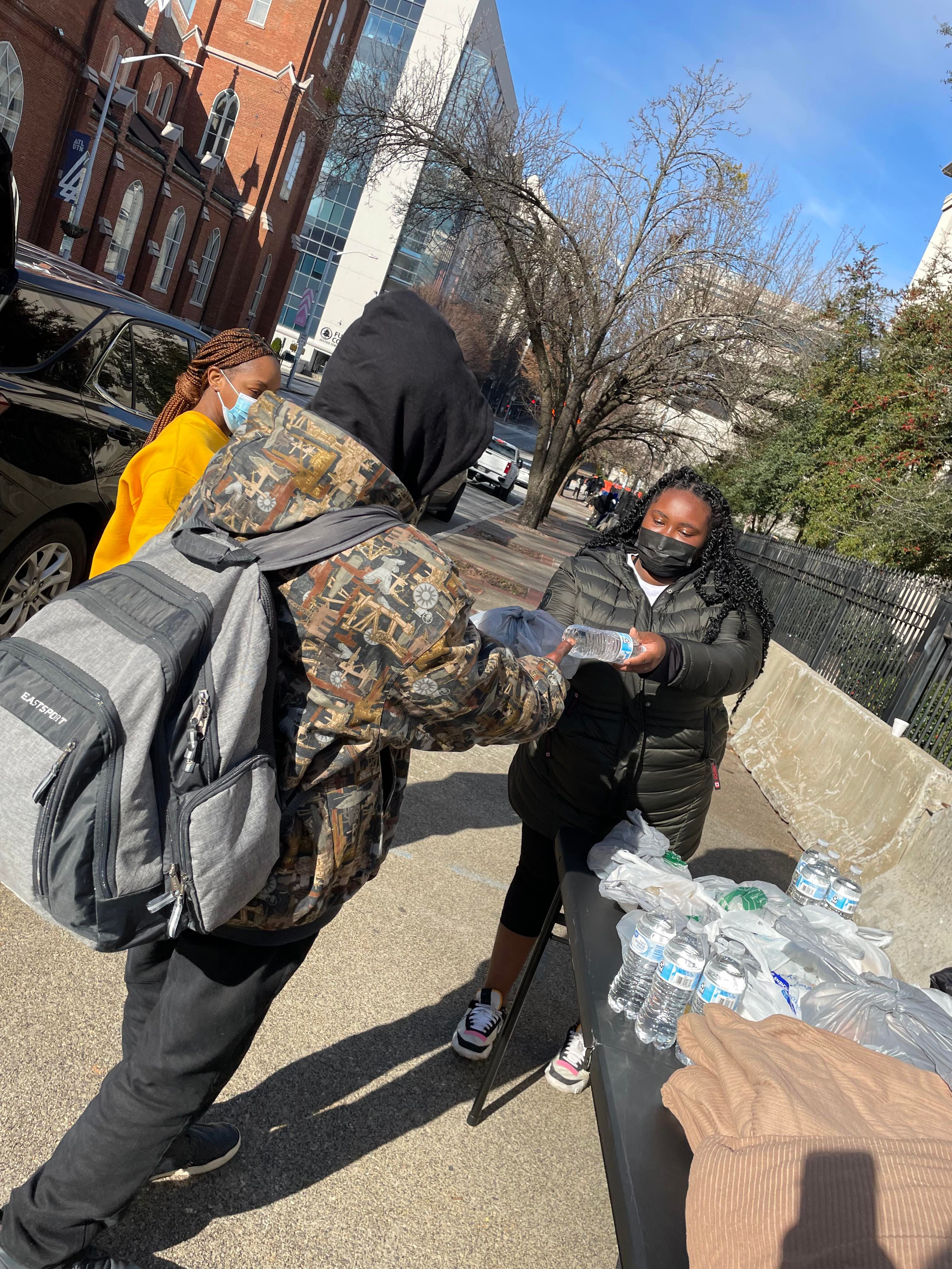 A volunteer handing a bottle of water to a community member