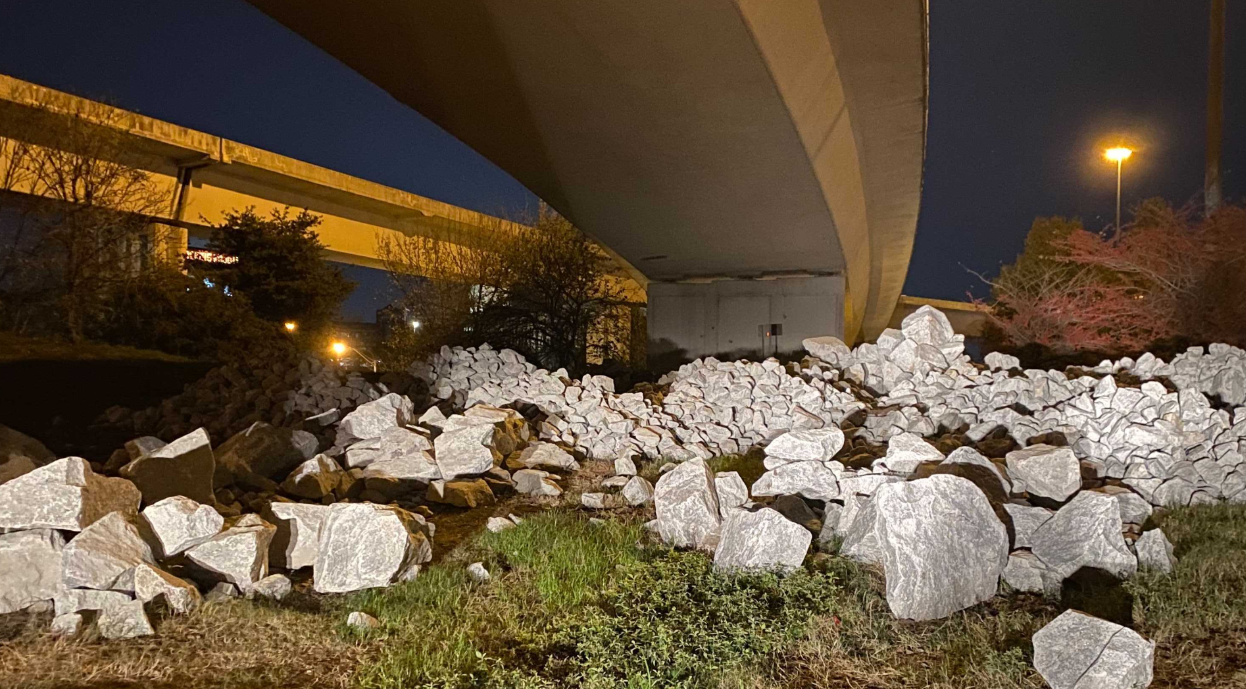 Large white boulders placed under a highway bridge at night