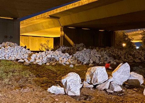A field of white rocks scattered under a highway overpass at night