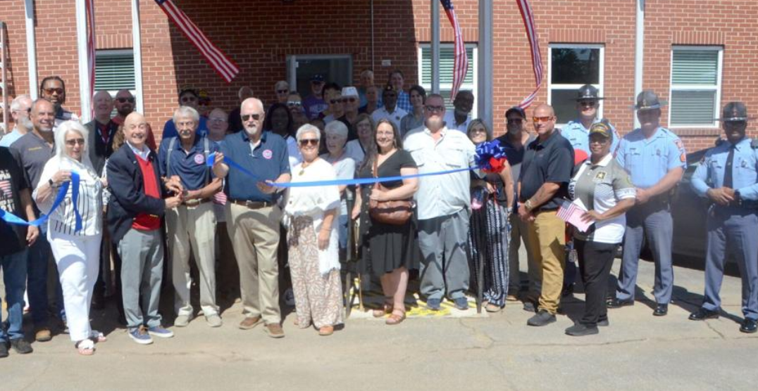 A ribbon-cutting ceremony with veterans and American flags at the Spalding County Veterans Center