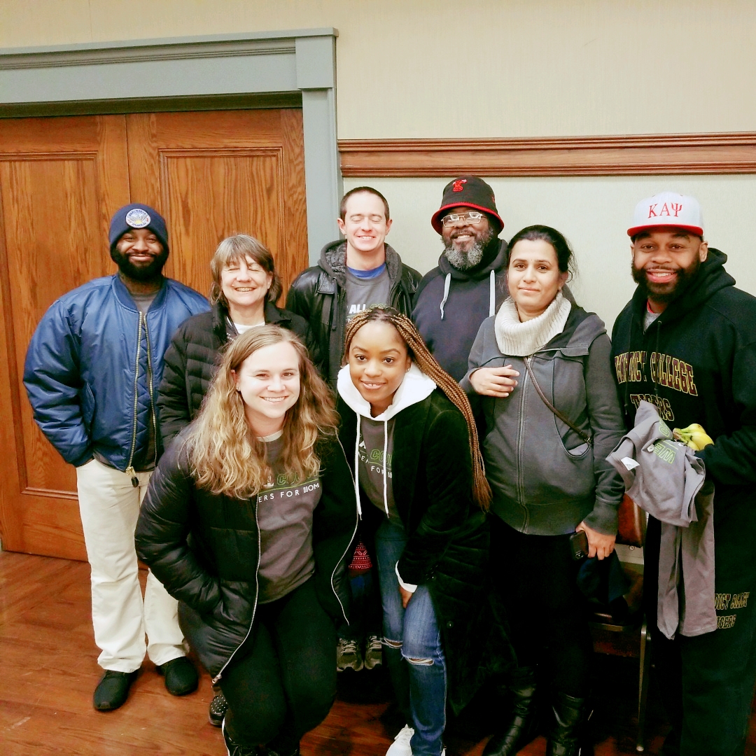 A group of Partners for Home volunteers in matching shirts and winter jackets posing together indoors during the 2019 PIT Count