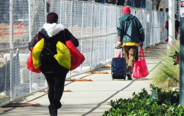 Volunteers carrying yellow and red Jo-Anne's House care bags down a downtown sidewalk