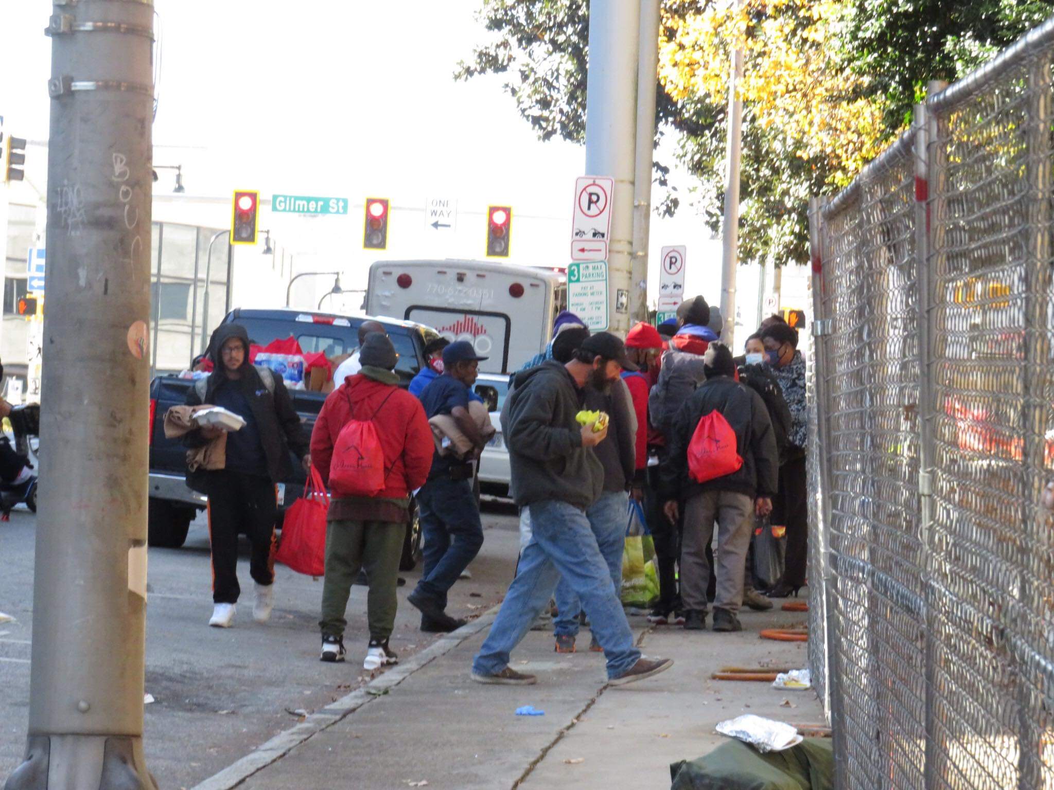 Community members carrying red Jo-Anne's House care bags along a downtown Atlanta sidewalk near Gilmer Street