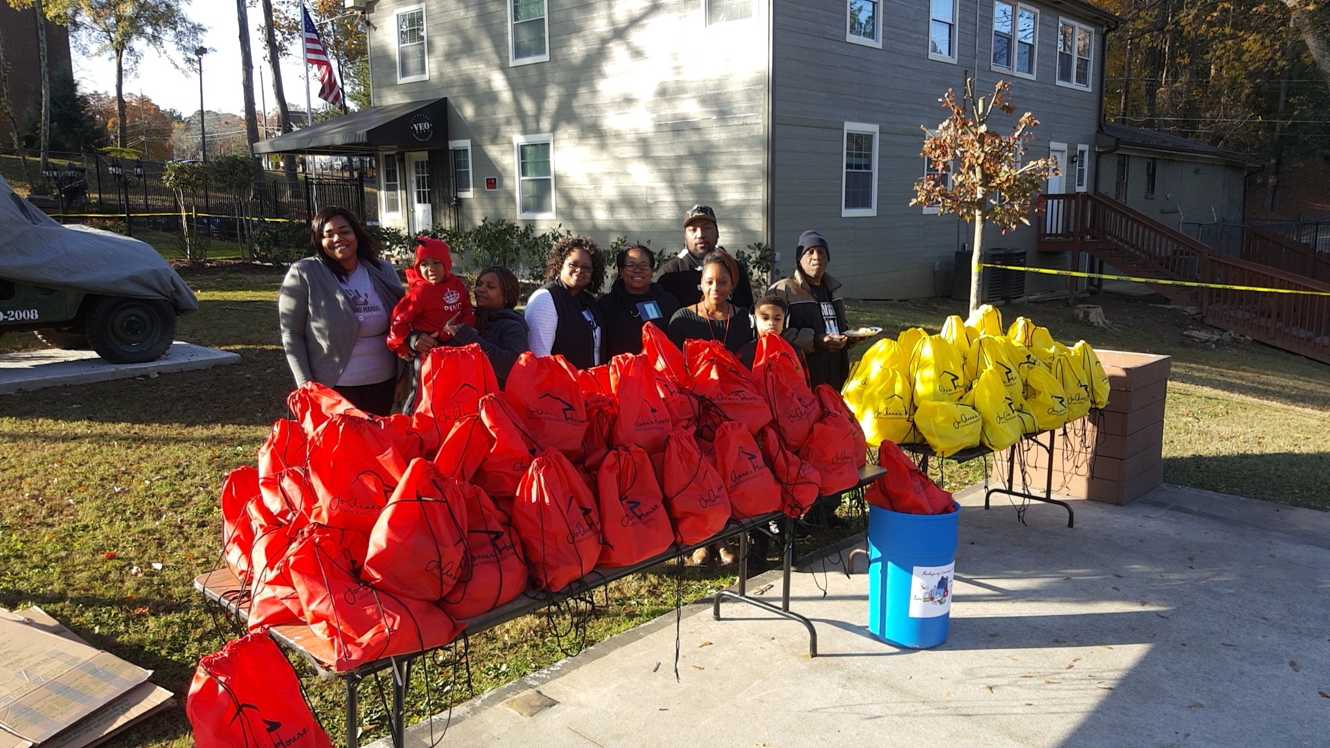 Jo-Anne's House volunteers standing behind tables of red and yellow care bags at the Veterans Empowerment Organization
