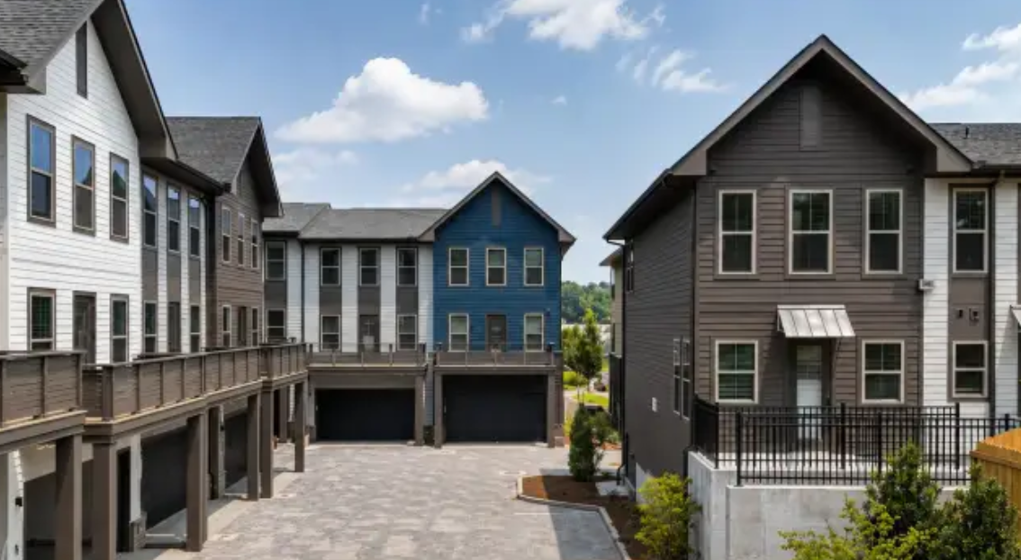 New townhomes with white, blue, and gray siding around a paved courtyard at Woodrow House in Atlanta's West End